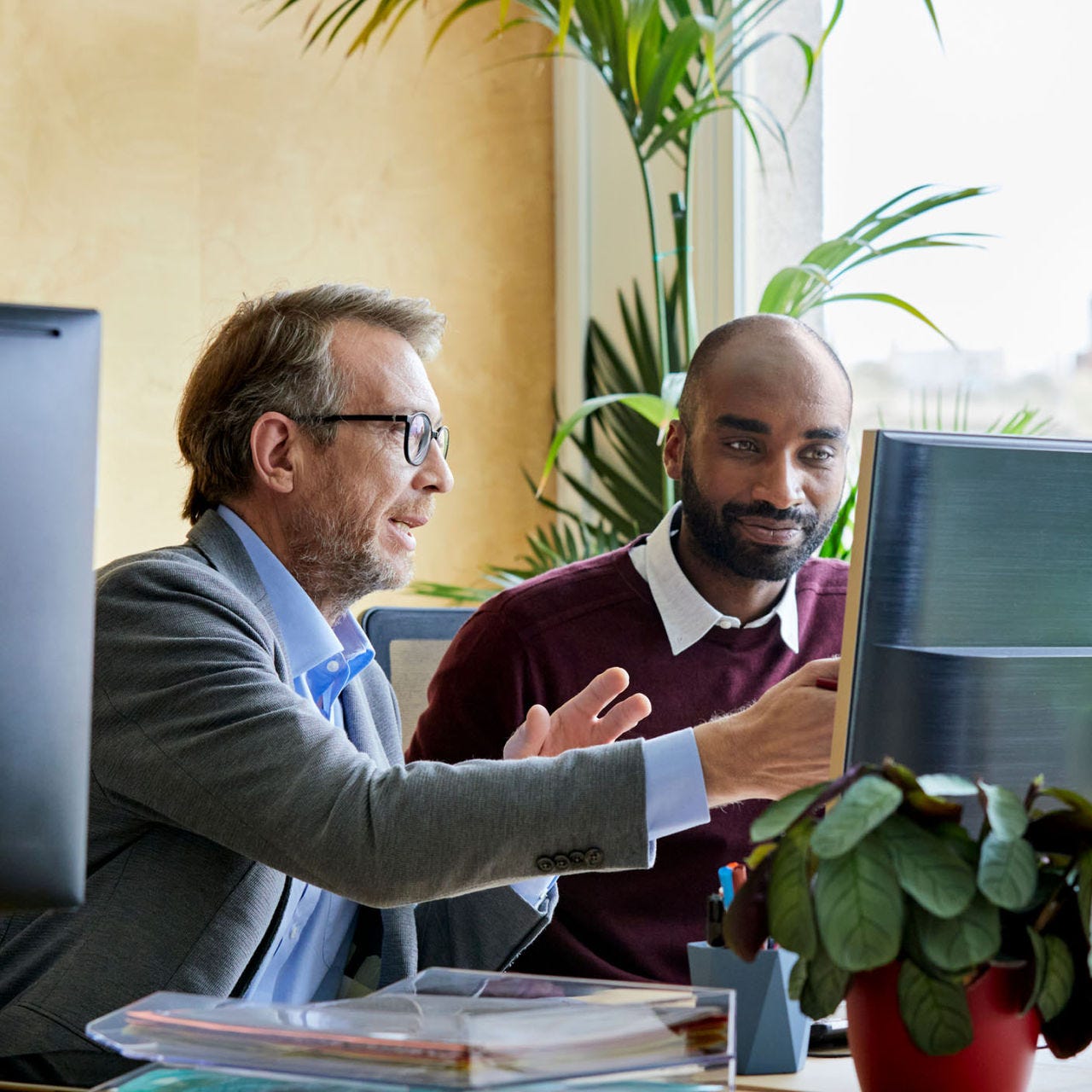 Two men looking at desktop screen and discussing.