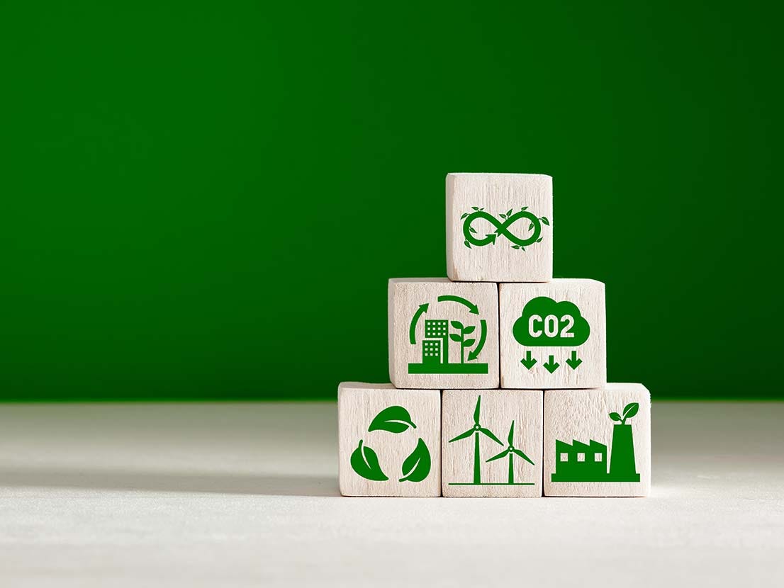 Circular economy and climate change concept. Business and environment sustainable development. Stacked wooden cubes with eco infinity and environment sustainable symbols on green background.